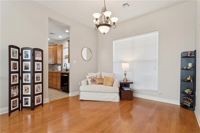 sitting room featuring light wood-type flooring, baseboards, visible vents, and a notable chandelier