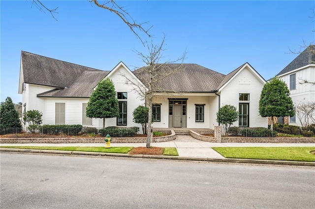 view of front of house with a shingled roof and fence