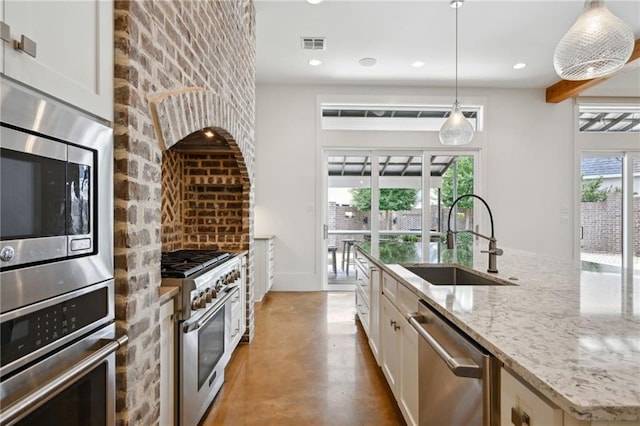 kitchen with finished concrete flooring, visible vents, appliances with stainless steel finishes, a kitchen island with sink, and a sink