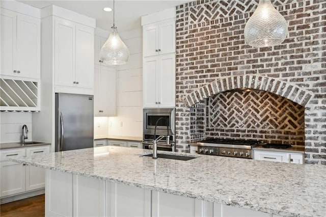 kitchen with white cabinets, backsplash, stainless steel appliances, and a sink