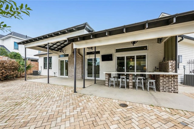 back of property with a patio area, brick siding, outdoor dry bar, and central air condition unit