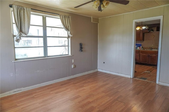 spare room featuring light wood-type flooring, a sink, baseboards, and a ceiling fan