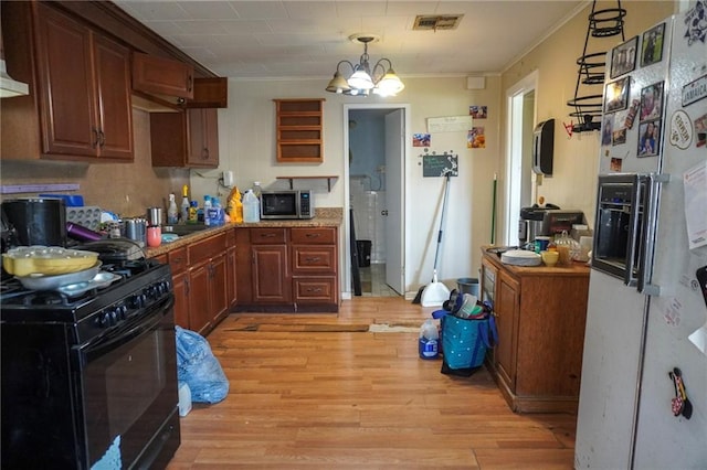 kitchen with stainless steel microwave, visible vents, light wood-style flooring, an inviting chandelier, and black range with gas stovetop