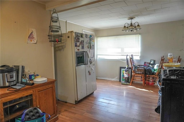 kitchen featuring a chandelier, white refrigerator with ice dispenser, ornamental molding, light wood-type flooring, and gas range oven