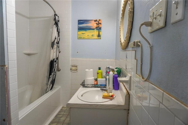 full bathroom with shower / bath combo with shower curtain, wainscoting, vanity, and tile walls