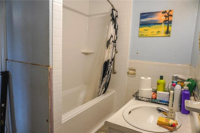 bathroom with shower / bath combination with curtain, a wainscoted wall, a sink, and tile walls