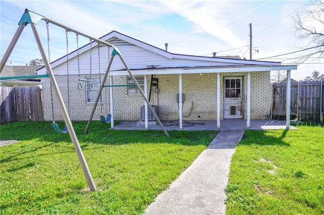 bungalow-style home with brick siding, fence, a front lawn, and a patio