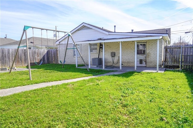 rear view of house with brick siding, a yard, a patio, central air condition unit, and a fenced backyard