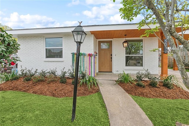 view of front of home featuring a front lawn, a porch, and brick siding