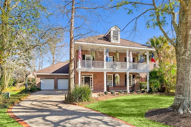 neoclassical / greek revival house featuring driveway, brick siding, covered porch, an attached garage, and a front lawn