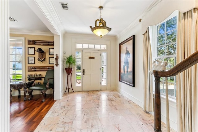 entrance foyer featuring baseboards, ornamental molding, and visible vents