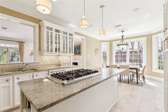 kitchen with a sink, stainless steel gas stovetop, visible vents, decorative backsplash, and white cabinets