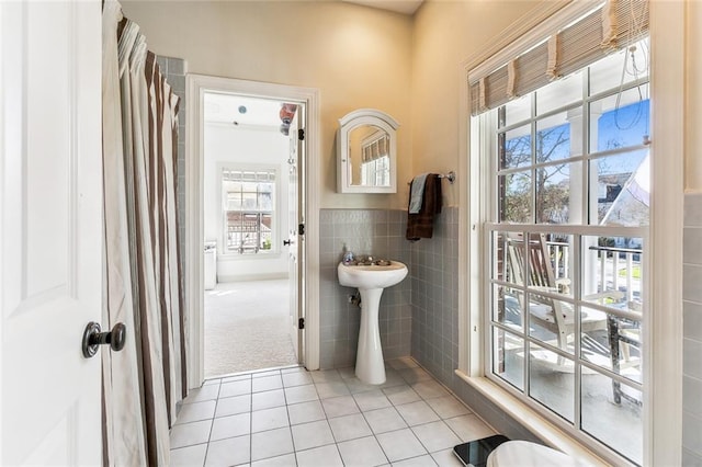 bathroom with tile walls, a wealth of natural light, tile patterned flooring, and a wainscoted wall