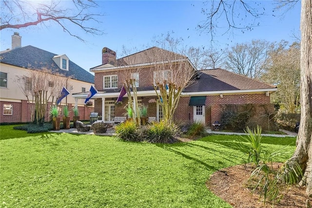 back of house with brick siding, a chimney, a lawn, and fence