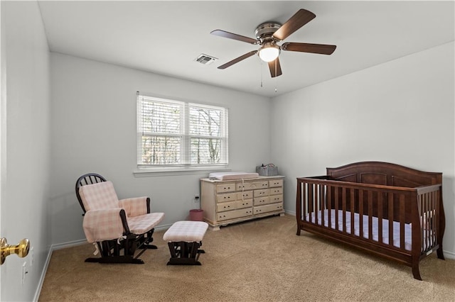 bedroom with carpet, visible vents, a crib, and baseboards