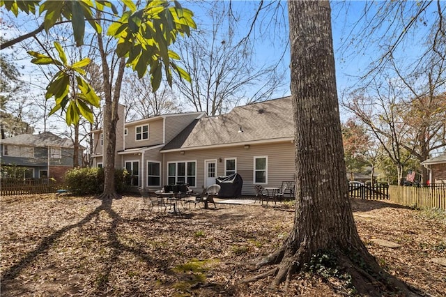 rear view of house with a patio, a chimney, fence, and roof with shingles