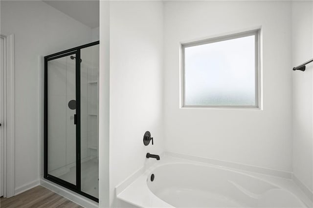 full bathroom with wood finished floors, a stall shower, and a garden tub