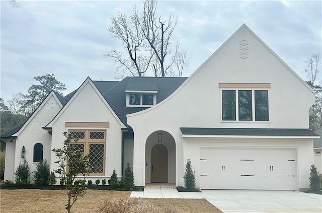 view of front facade with concrete driveway, an attached garage, and stucco siding