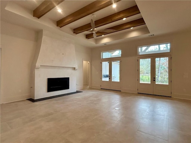 unfurnished living room with baseboards, beamed ceiling, a high ceiling, french doors, and a high end fireplace