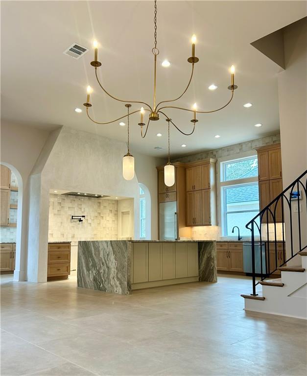 kitchen with arched walkways, recessed lighting, a spacious island, visible vents, and tasteful backsplash