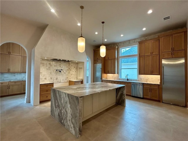 kitchen with light stone counters, a sink, visible vents, appliances with stainless steel finishes, and decorative backsplash