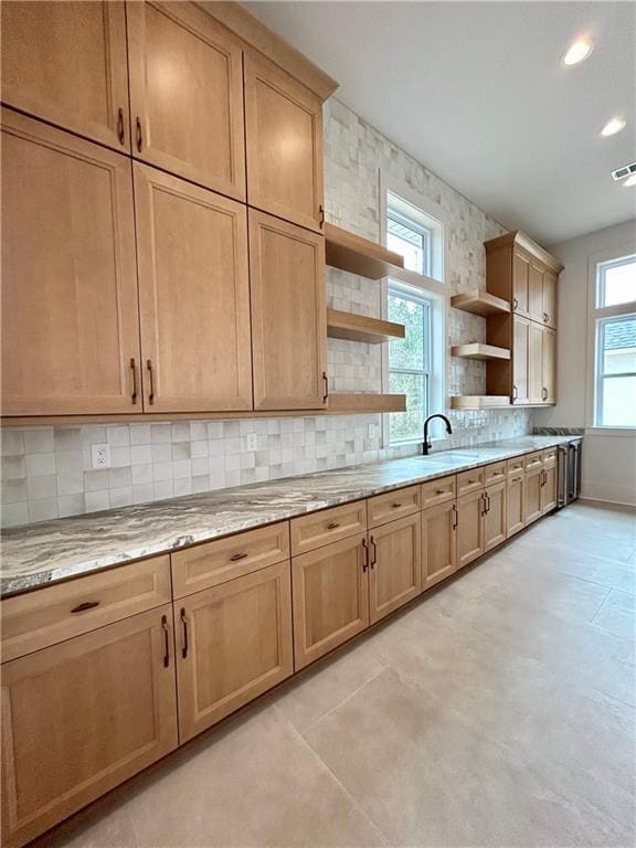 kitchen featuring light stone counters, open shelves, recessed lighting, backsplash, and a sink