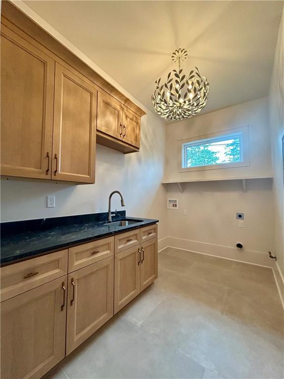 kitchen featuring hanging light fixtures, dark stone countertops, a sink, and baseboards