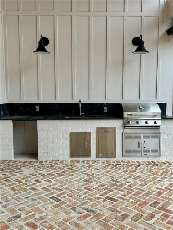 kitchen with brick floor, white cabinets, and a sink