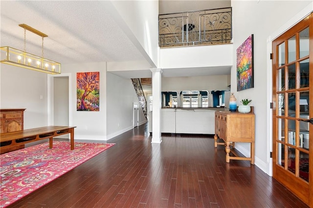 foyer with a textured ceiling, wood finished floors, a towering ceiling, and baseboards