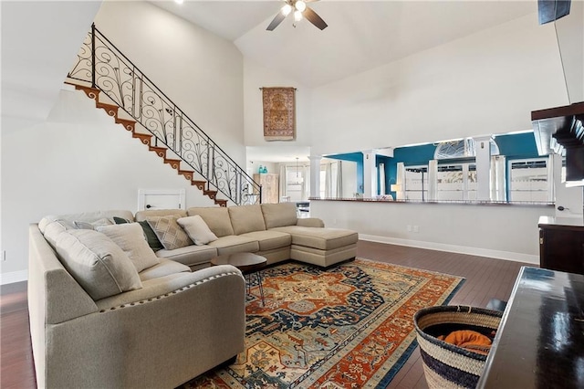 living area featuring stairway, dark wood-type flooring, ceiling fan, high vaulted ceiling, and ornate columns