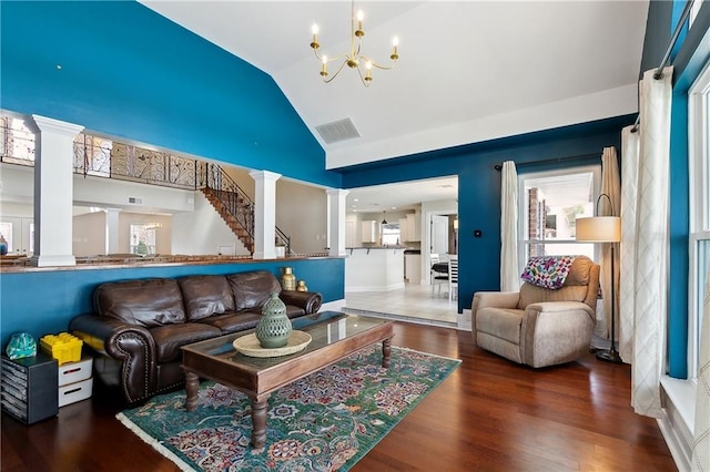 living area featuring lofted ceiling, decorative columns, visible vents, and wood finished floors