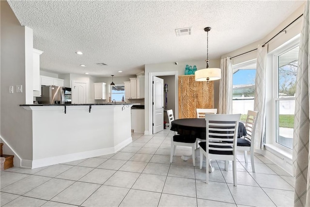 dining room with light tile patterned flooring, visible vents, and baseboards