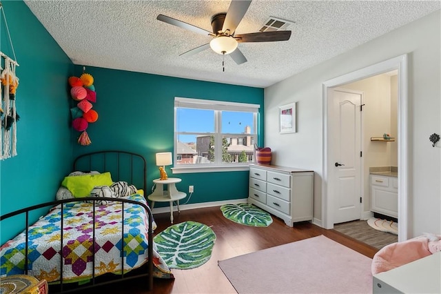 bedroom with visible vents, ceiling fan, a textured ceiling, wood finished floors, and baseboards