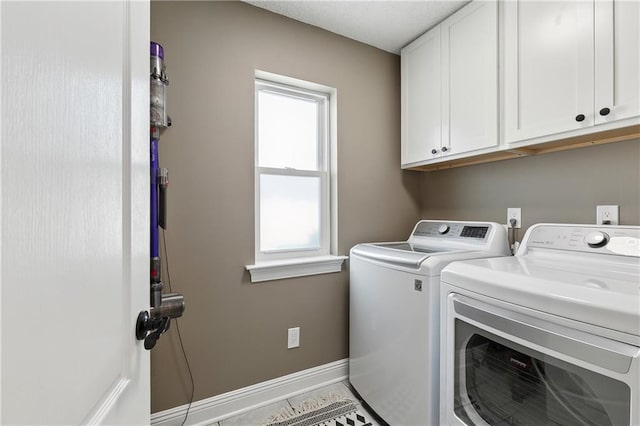 washroom with separate washer and dryer, cabinet space, and baseboards