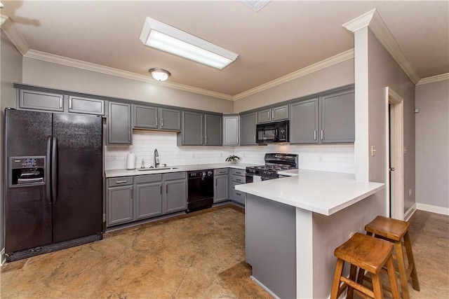 kitchen with a breakfast bar area, a peninsula, a sink, gray cabinets, and black appliances