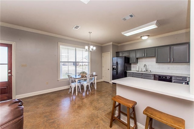 kitchen featuring a breakfast bar, a sink, light countertops, black refrigerator with ice dispenser, and tasteful backsplash