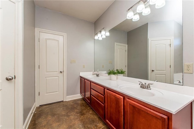 bathroom with concrete flooring, double vanity, a sink, and baseboards