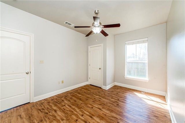 unfurnished room featuring baseboards, visible vents, ceiling fan, and wood finished floors