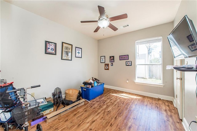 exercise room with visible vents, ceiling fan, baseboards, and wood finished floors