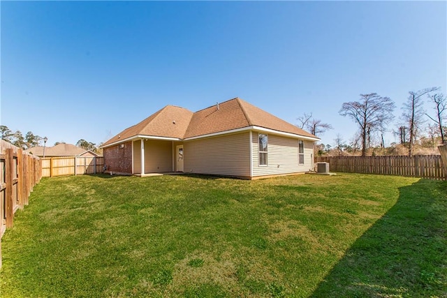 rear view of house featuring central air condition unit, a fenced backyard, and a yard