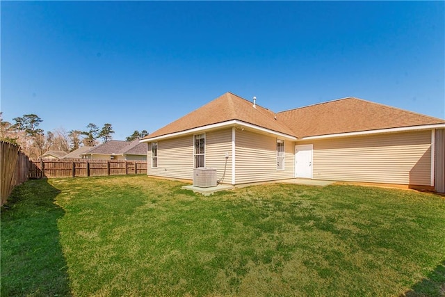 rear view of property with a fenced backyard, central AC, and a lawn