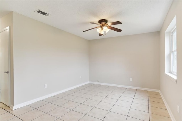 spare room featuring a textured ceiling, baseboards, visible vents, and a ceiling fan