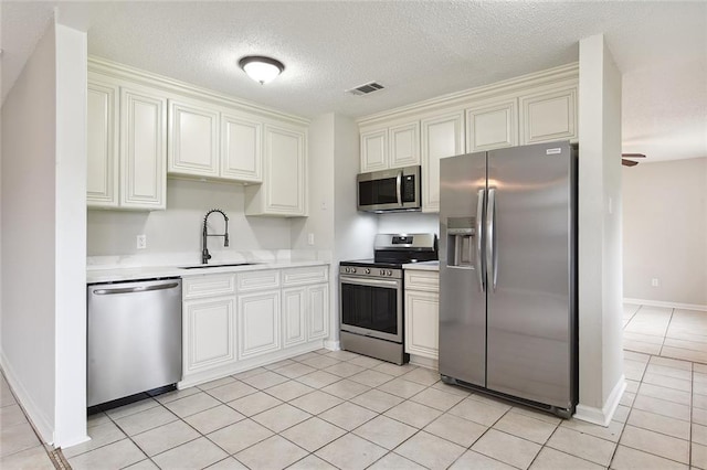 kitchen featuring stainless steel appliances, light countertops, visible vents, light tile patterned flooring, and a sink