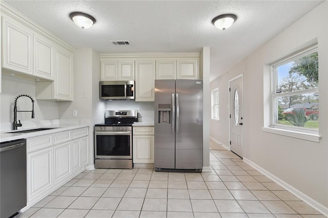 kitchen featuring stainless steel appliances, light countertops, a sink, and visible vents