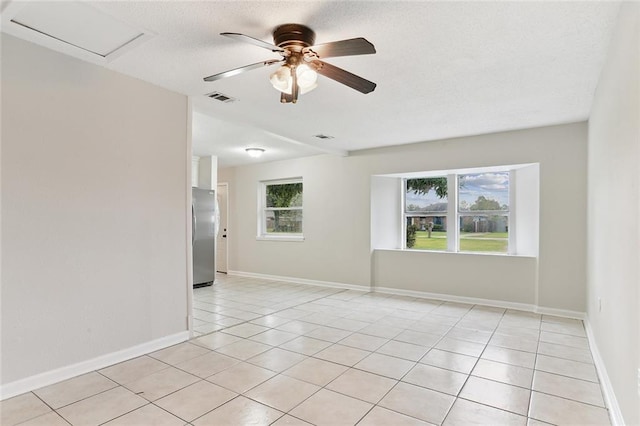 unfurnished room featuring light tile patterned floors, plenty of natural light, visible vents, and attic access