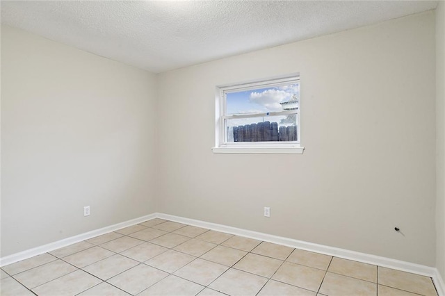 spare room with a textured ceiling, baseboards, and light tile patterned floors