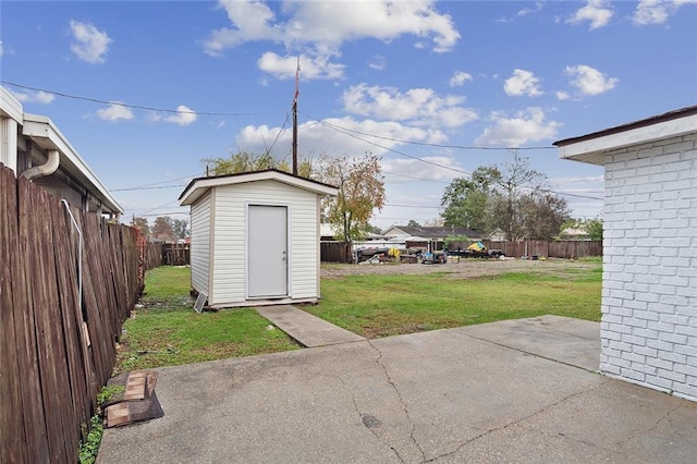 view of yard featuring a storage shed, a patio area, a fenced backyard, and an outbuilding