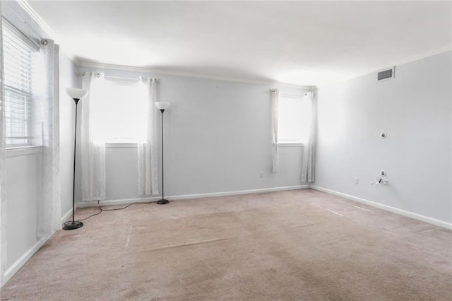 empty room with baseboards, carpet floors, visible vents, and crown molding