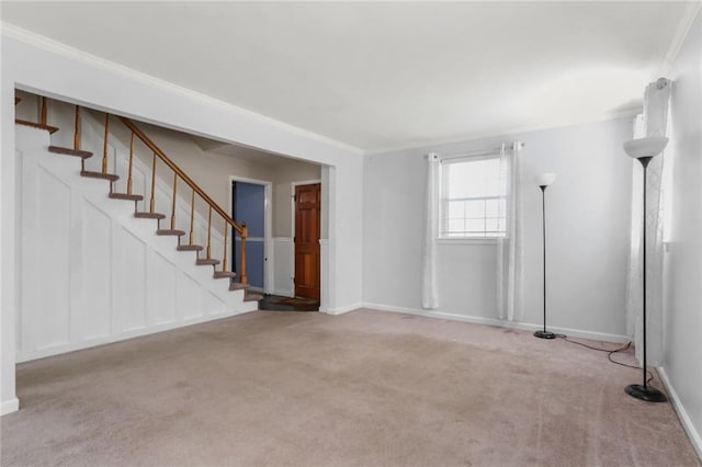 unfurnished living room with carpet floors, crown molding, baseboards, and stairs