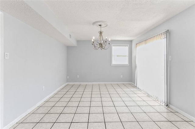 spare room with a textured ceiling, baseboards, and an inviting chandelier